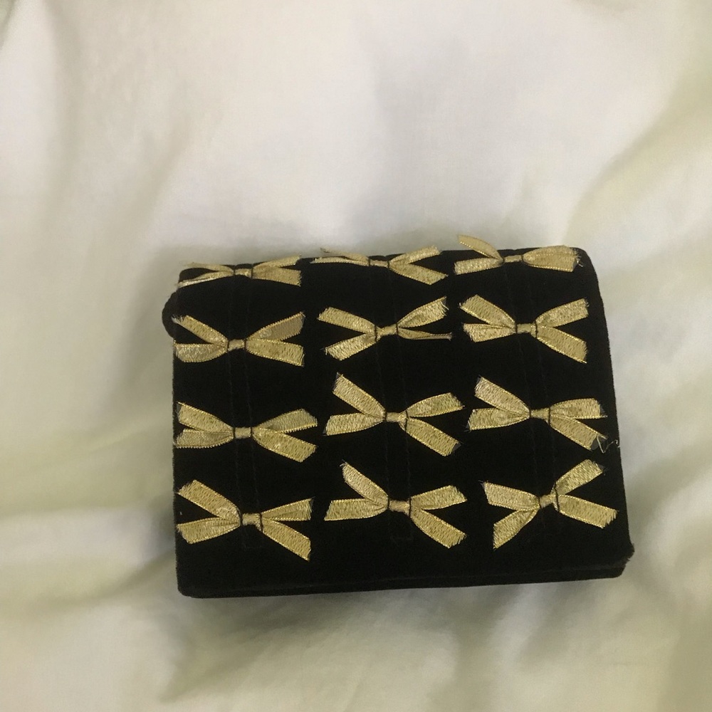 Small velvet clutch with delicate gold bows.